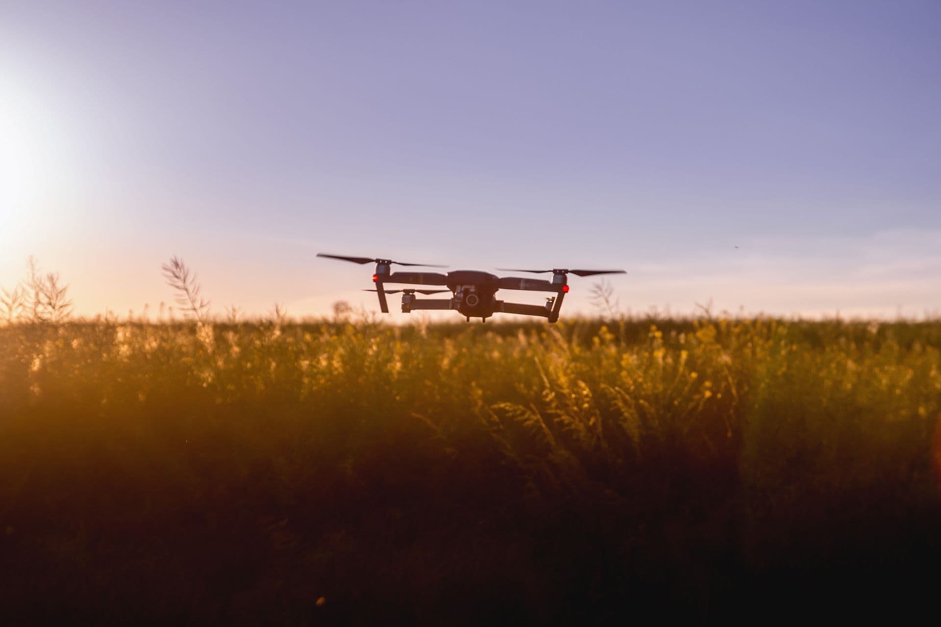Drone flying over a field at sunset